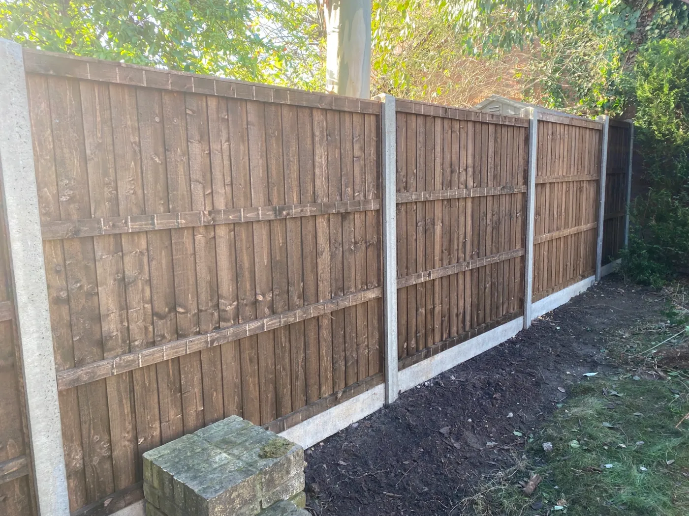 Brown closeboard fence panels fitted with concrete posts and gravel boards in a back garden